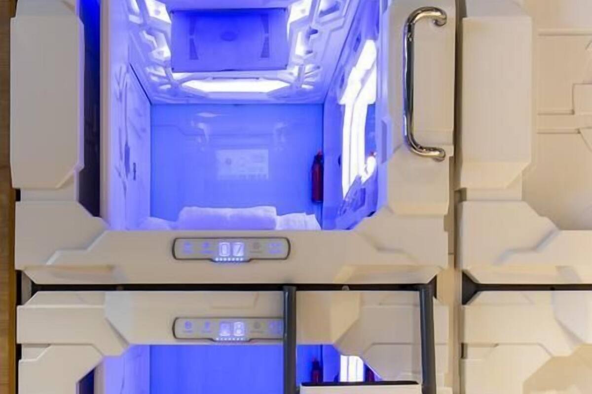 Un hotel cápsula con dos habitaciones, cada una con una cama y un panel de control.