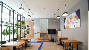 A modern office space with wooden tables and chairs, a staircase with blue accents, and hanging plants. - Spacehotel-Karlsruhe  (Karlsruhe)