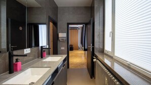 A modern bathroom with dual sinks, a large mirror, and a walk-in shower. - Spacehotel-Karlsruhe  (Karlsruhe)