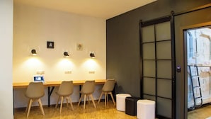 A room with a wooden floor, a desk with a computer, four chairs, and a sliding door with a view of a white structure outside. - Spacehotel-Karlsruhe  (Karlsruhe)