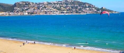 A beach with a view of a hill with buildings.