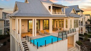 A two-story house with a swimming pool, large windows, and a covered patio area. - 1 HOUSE OFF THE BEACH! Private Pool, LSV/Golf Cart, Bikes, Games, Gym! Sleeps 22! (Santa Rosa Beach)