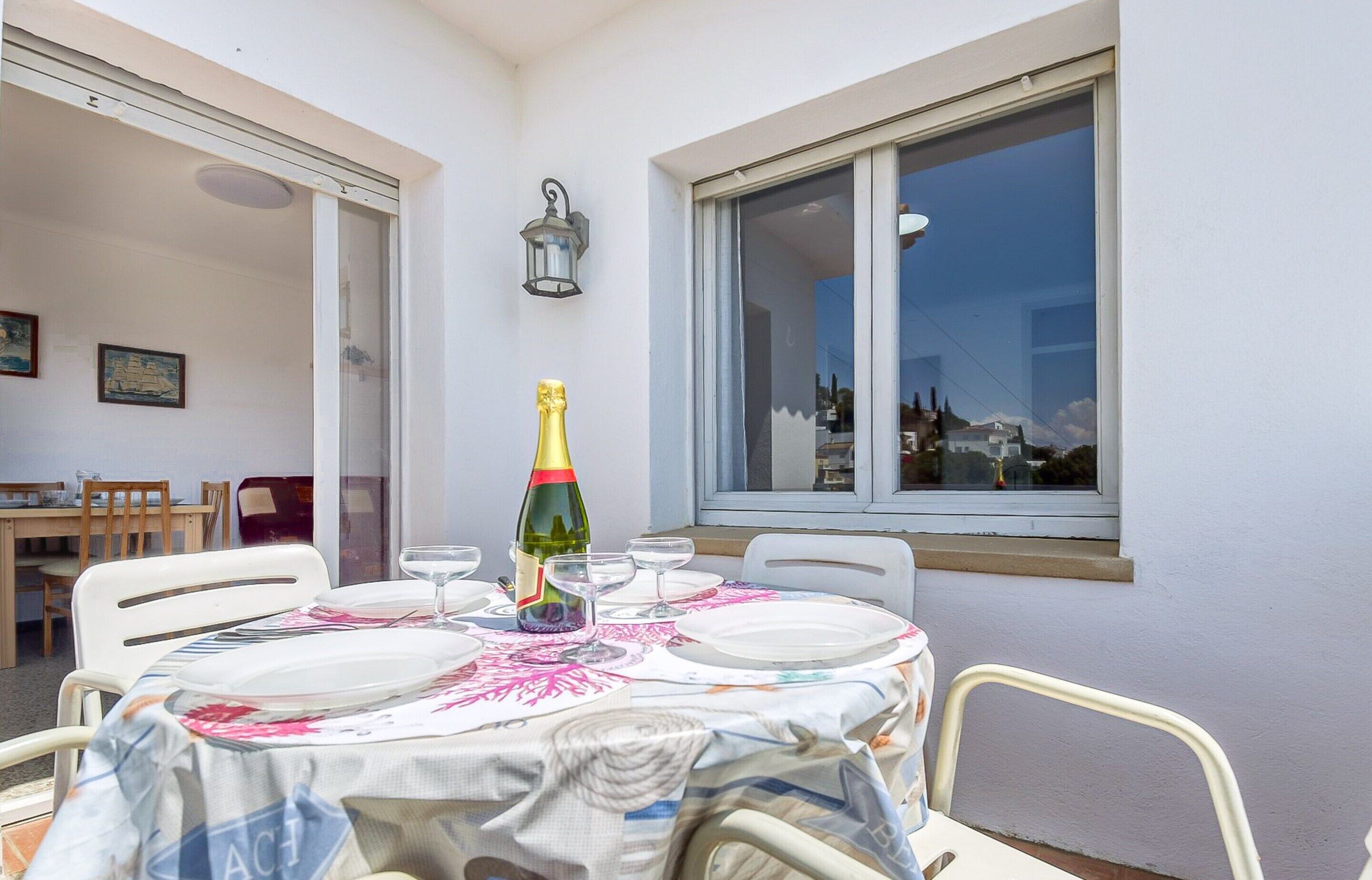 A dining table set with plates, a bottle of champagne, and glasses, positioned in a room with a window and a door leading to another area.