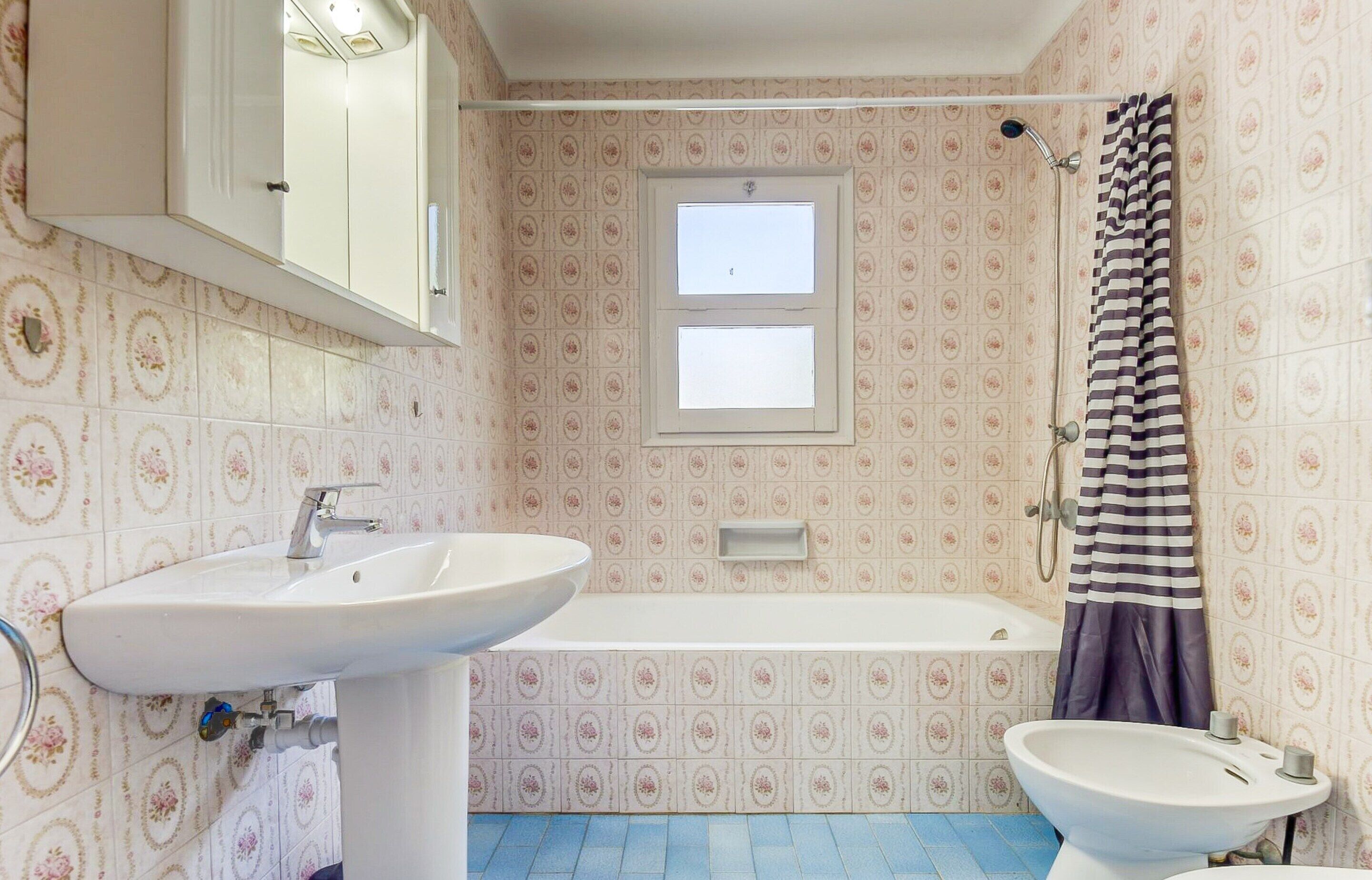A bathroom with a sink, a bathtub, and a shower curtain.