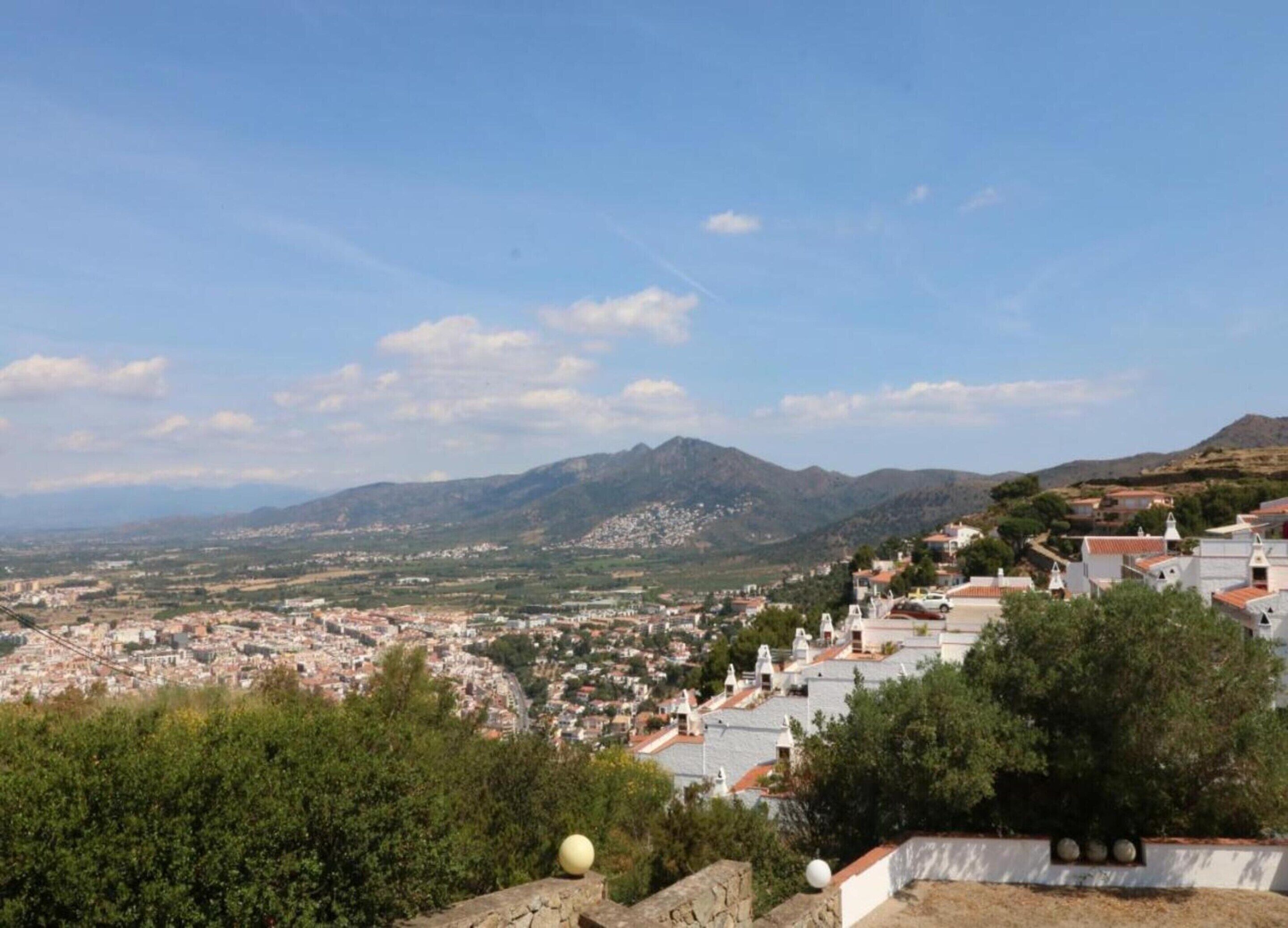 A town with white buildings and a mountain range in the background.