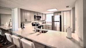 A modern kitchen with white cabinets, stainless steel appliances, and a central island with seating.