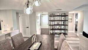 A modern dining area with a dark wooden table, grey upholstered chairs, and pendant lighting.