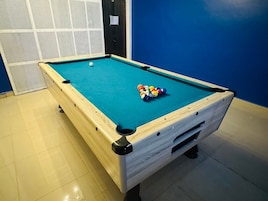Uma mesa de bilhar com pano branco, uma bola branca e um suporte com bolas de bilhar.
