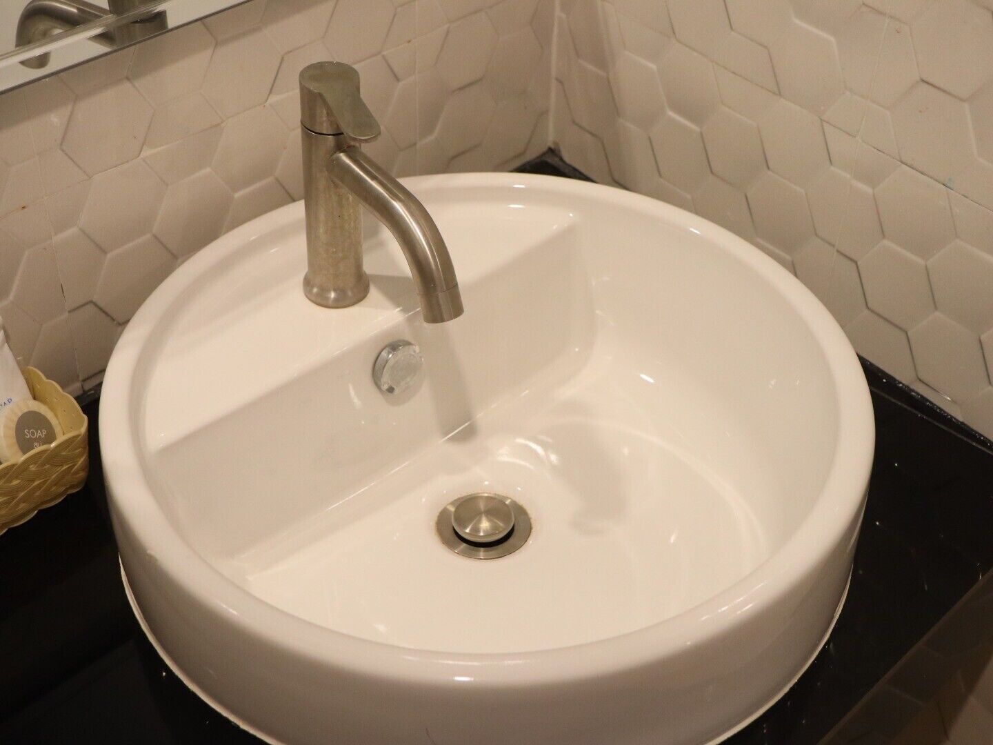 A white bathroom sink with a single faucet, a soap dish, and a drain.