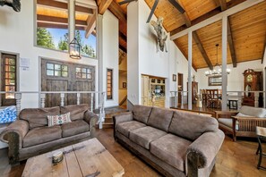 Ein geräumiges Wohnzimmer mit zwei braunen Sofas, einem Holztisch und einer Holzzielendecke mit sichtbaren Balken.