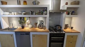 Una cocina compacta con lavavajillas, estufa, horno y una variedad de utensilios y electrodomésticos sobre las encimeras.