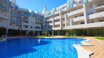 Una piscina rodeada por un edificio de varios pisos con balcones.