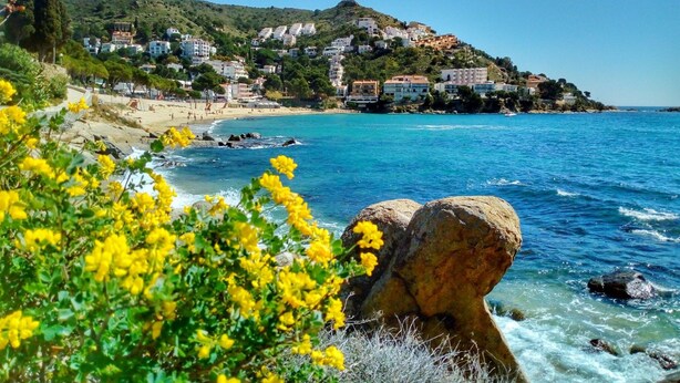 A coastal town with buildings on a hillside, a sandy beach, and clear blue waters. - Charming Apartment With Patio (Roses)