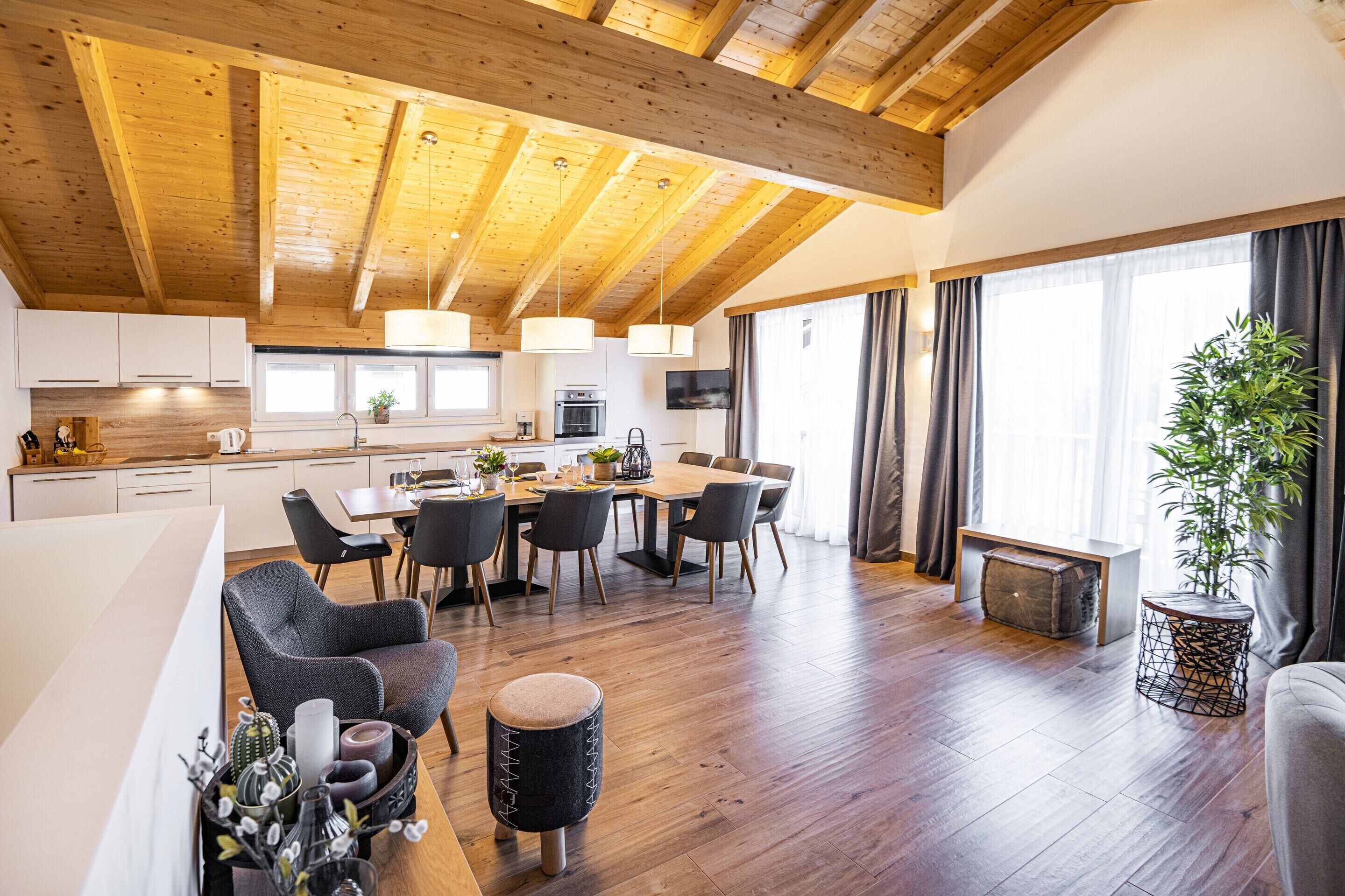 A spacious living area with a wooden ceiling, a dining table, and a comfortable seating arrangement.