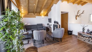 A modern living room with a wooden ceiling, grey sofas, a coffee table, and a potted plant. - Mountain-view Chalet in Wagrain (Wagrain)
