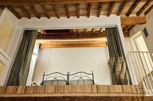 Un dormitorio con techo de madera, estructura de cama metálica y vista a un balcón.