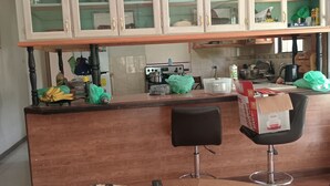 Une cuisine avec un plan de travail en bois, deux tabourets de bar, un réfrigérateur et des placards au-dessus du plan de travail.