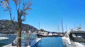 A marina with boats docked, a clear blue sky, and a hillside in the background. - Apartment in Roses With Beachfront View (Roses)