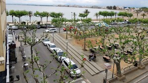 A parking area with cars, outdoor seating, and a view of the sea. - Apartment in Roses With Beachfront View (Roses)