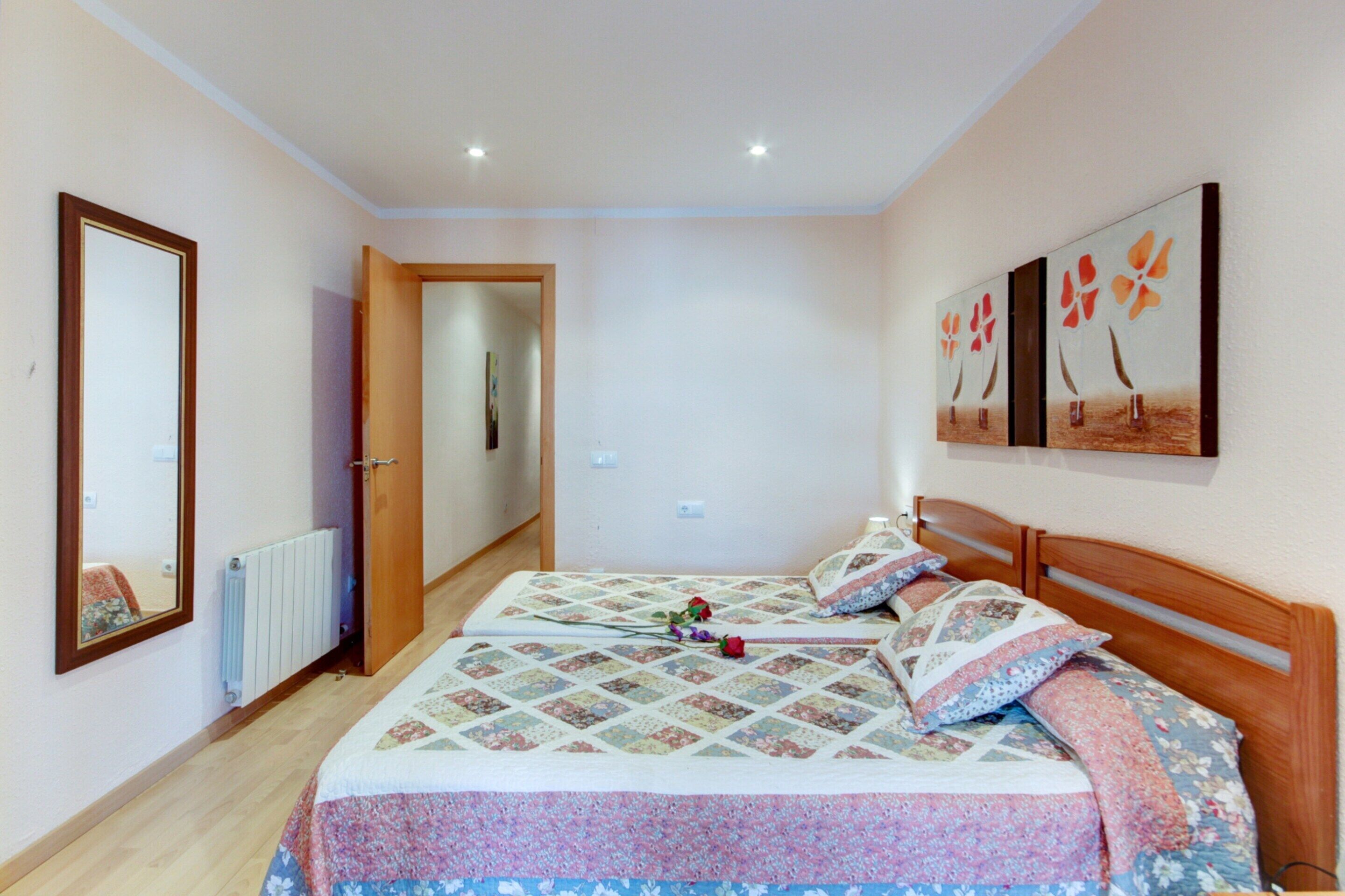 Quarto com cama de madeira, colcha e um quadro na parede.