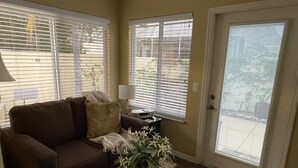 A living room with a brown sofa, a small side table, a lamp, and a wicker basket with flowers.