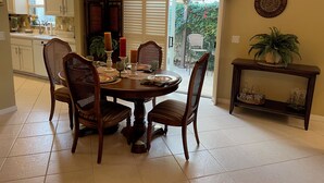 A dining area with a round table, four chairs, and a chandelier.