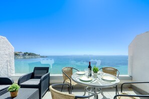 Un balcone con mobili in vimini, un tavolo apparecchiato per due persone e vista sul mare.