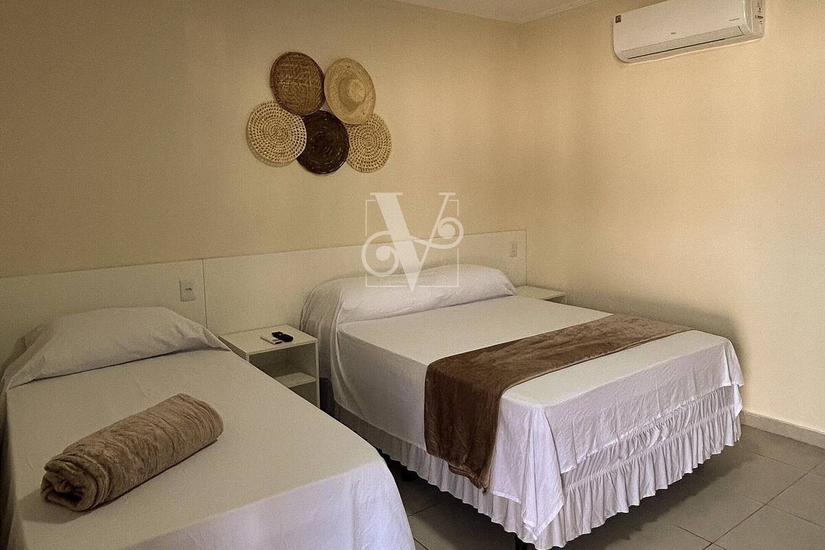 A hotel room with two beds, a ceiling fan, and a wall-mounted air conditioner.