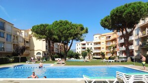 A swimming pool surrounded by apartment buildings, with trees and lounge chairs. - Bright Flat Near Nature Park (Castello d'Empuries)