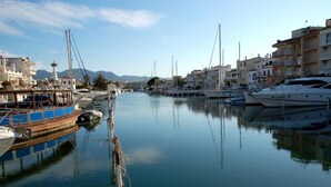 A marina with boats docked along the water, surrounded by buildings and mountains in the background. - Bright Flat Near Nature Park (Castello d'Empuries)