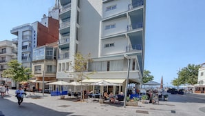 A multi-story building with balconies, outdoor seating, and a pedestrian area. - Apartment in Roses Near the Beach (Roses)
