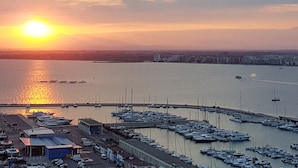 A marina with boats docked, a pier, and buildings in the background during sunset. - Apartment in Roses Near the Beach (Roses)