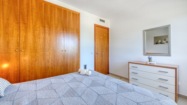 A bedroom with a large bed, wooden wardrobe, a dresser, and a mirror on the wall. - Apartment in Roses Near Sandy Beach (Roses)