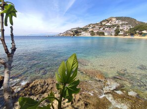 A coastal view with clear water, rocky shore, and a hillside with buildings. - Apartment in Roses Near Sandy Beach (Roses)
