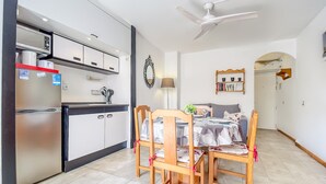 Uma cozinha moderna com eletrodomésticos de aço inoxidável, uma área de refeições com cadeiras e mesa de madeira, e um ventilador de teto.