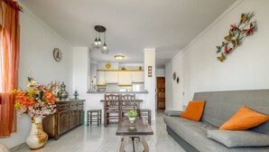 A modern living room with a grey sofa, a dining table, and a kitchen in the background. - Apartment in Roses Near Cap de Creus (Roses)