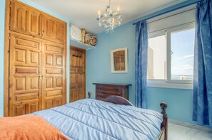 Ein Schlafzimmer mit einem Bett, einem Holzschrank, einem Schminktisch und einem Fenster mit Vorhängen.