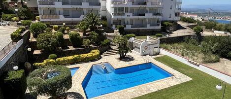 A hotel with a swimming pool, well-maintained gardens, and a view of the sea.