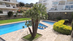 A pool area with stone flooring, palm trees, and a well-maintained hedge. - Apartment in Roses Near Cap de Creus (Roses)