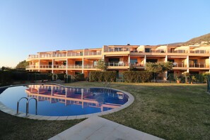 Ein mehrstöckiges Hotel mit Pool, Balkonen und einem angelegten Garten.