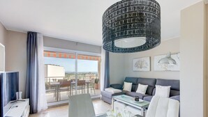 Ein modernes Wohnzimmer mit Sofa, Esstisch und großem Fenster.
