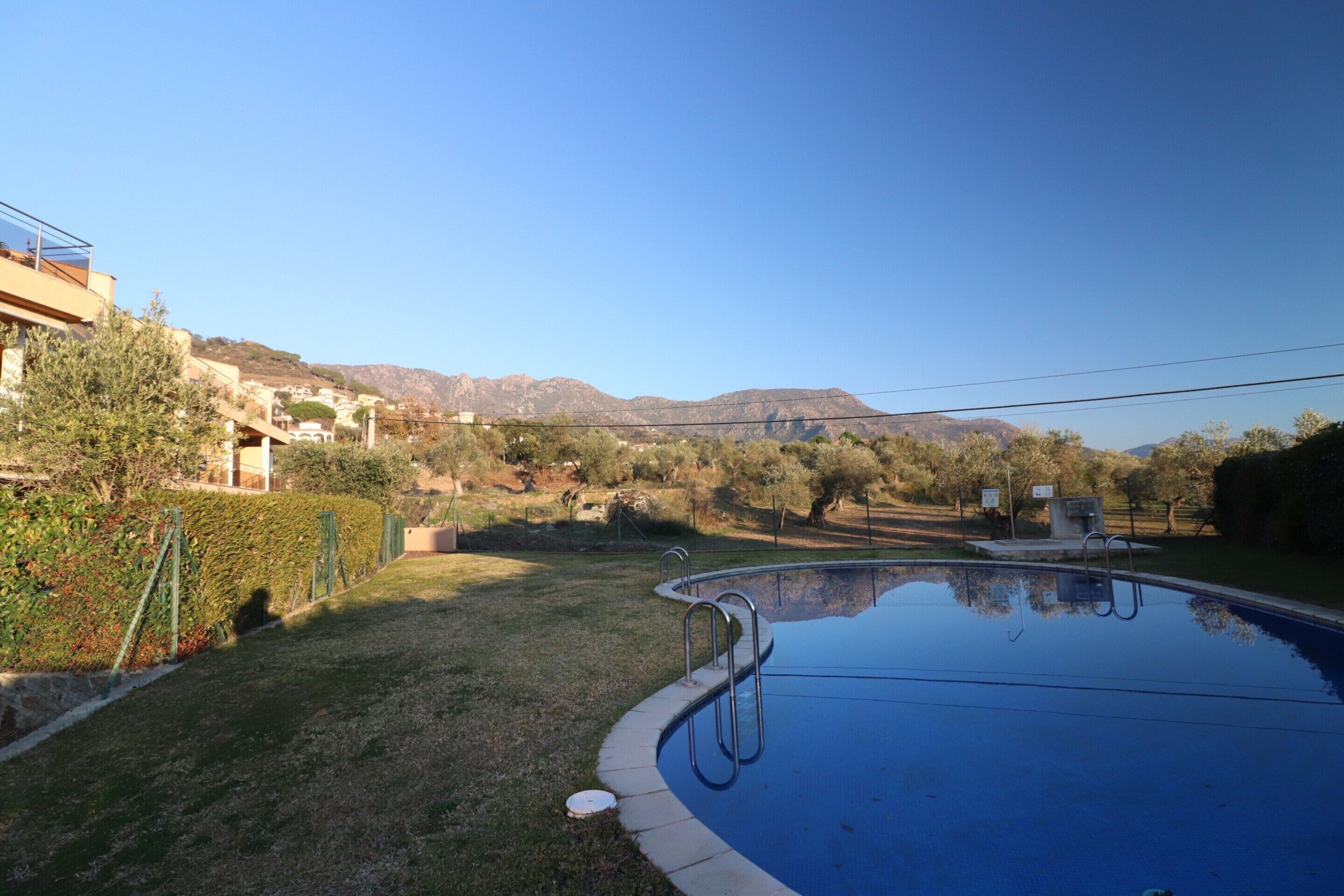 A swimming pool with a clear view of the surrounding landscape, including mountains and a residential area.