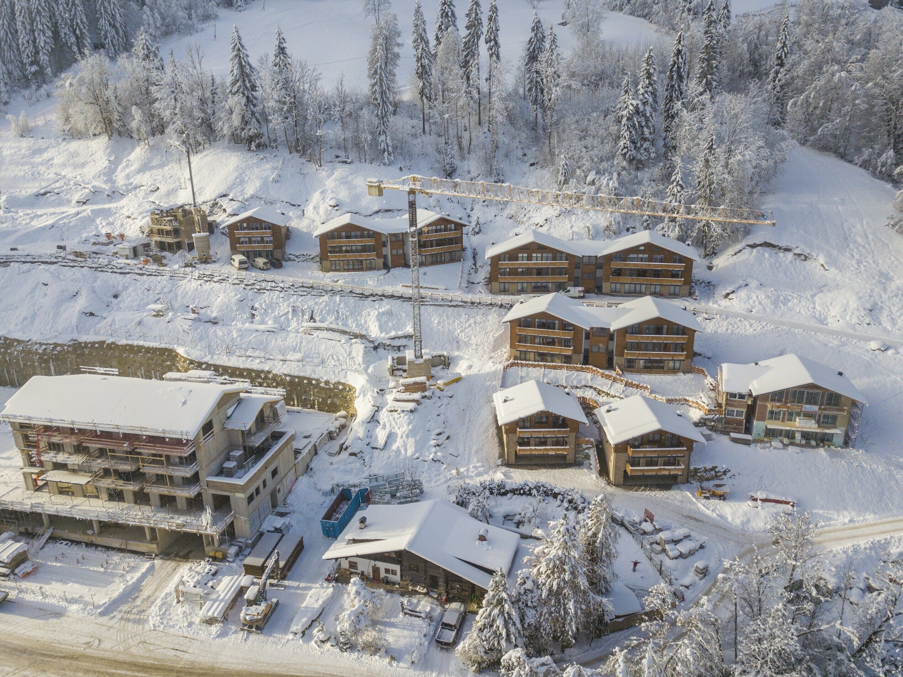 A snow-covered ski resort with multiple wooden lodges, a swimming pool, and a ski lift.