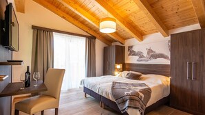A bedroom with a wooden ceiling, a bed with a blanket, a desk with wine glasses, and a wall-mounted TV. - Apartment in Salzburg With Private Balcony (Wagrain)