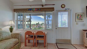 A room with a window overlooking a playground, a ceiling fan, a clock, and a framed picture on the wall. - Directly on the Gulf - Unit  9 - 1 Bedroom - Ground Floor - Sleeps up to 4 (Venice)
