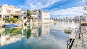 A waterfront property with a dock, calm water, and buildings with balconies and tiled roofs. - Rustic Chic w/ Mooring Spot (Castello d'Empuries)