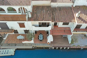 A multi-story building with a tiled roof, a balcony with a table and chairs, and a pool area. - Rustic Chic w/ Mooring Spot (Castello d'Empuries)