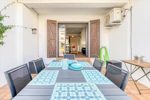 A patio with a table set for dining, surrounded by chairs, and an air conditioning unit on the wall. - Rustic Chic w/ Mooring Spot (Castello d'Empuries)