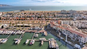 A marina with numerous boats docked, a coastal town with buildings, and a clear view of the sea. - Rustic Chic w/ Mooring Spot (Castello d'Empuries)