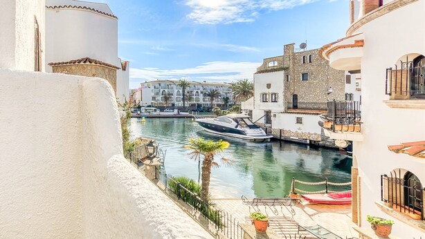 A canal with boats, white buildings, and a stone tower. - Rustic Chic w/ Mooring Spot (Castello d'Empuries)